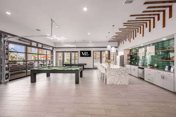 A billiard table is in the middle of a room with a pool table and a foosball table.