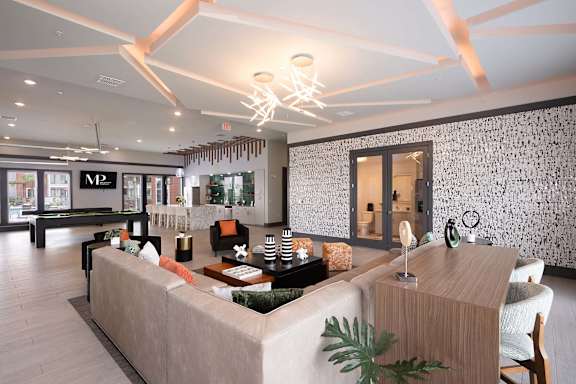 A living room with a large couch and a patterned wallpaper.