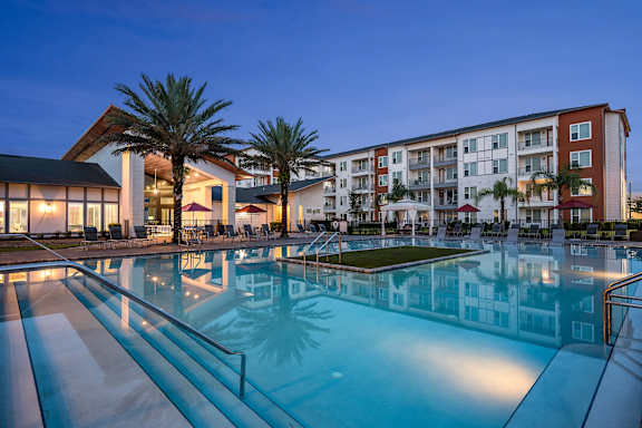 A large swimming pool in front of a multi-story apartment building.