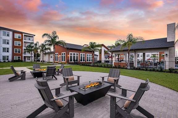A fire pit surrounded by chairs in a courtyard.