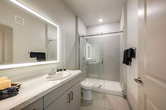 A bathroom with a sink, mirror, and shower.