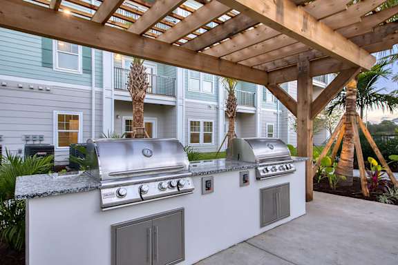 A white outdoor kitchen with a grill and sink.