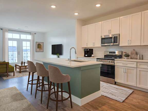 A kitchen with a green island and white cabinets.