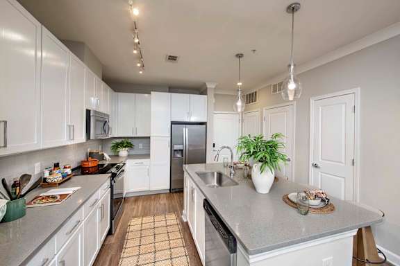 A kitchen with white cabinets and a grey countertop.