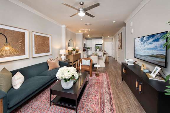 A living room with a grey couch, a coffee table, and a flat screen TV mounted on the wall.
