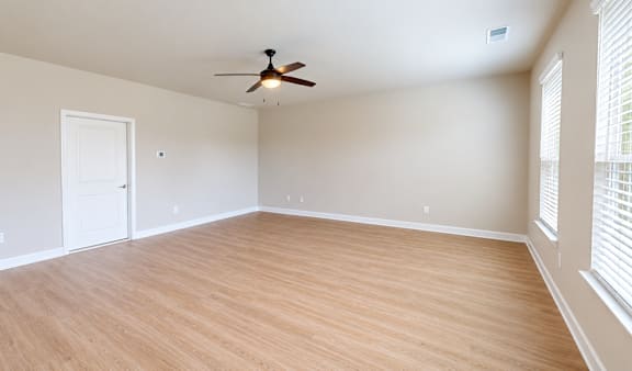 A room with a ceiling fan and wooden flooring.
