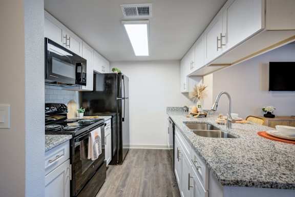 A kitchen with black appliances and a granite countertop.