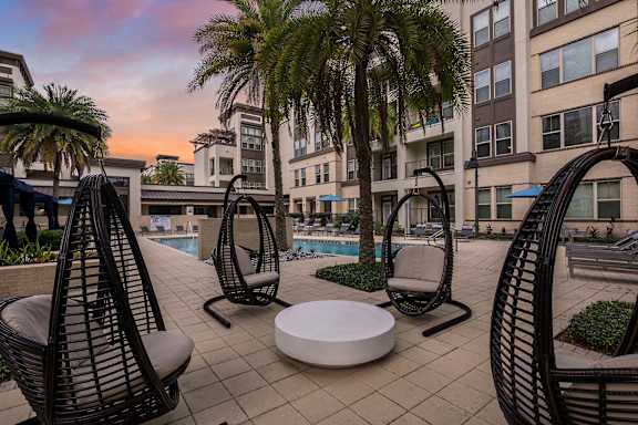 A patio with chairs and a table is surrounded by buildings.