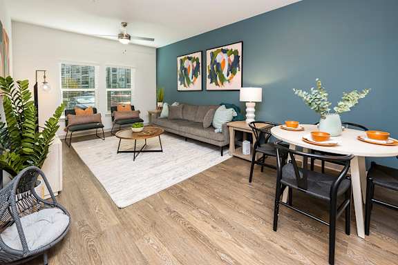 A living room with a grey couch, a white table, and a plant.