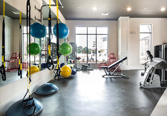 A gym with a variety of equipment including a weight bench, a leg press machine, and a rowing machine.
