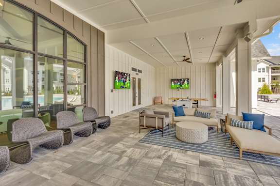 A spacious room with a long couch and a round ottoman in the center.