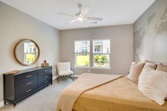 A bedroom with a bed, dresser, chair, and window.
