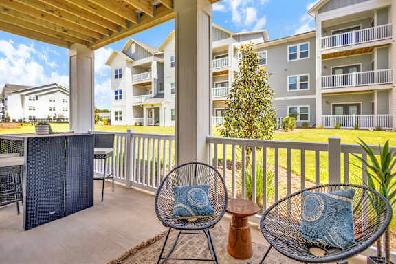 A patio with a chair and a table with a blue pillow on it.