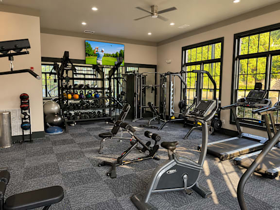 A spacious gym with a variety of equipment including treadmills, weights, and a television.