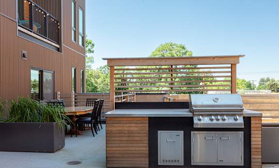 A modern outdoor kitchen with a grill and seating area.