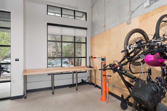 A bicycle is parked in a room with a bench and a window.