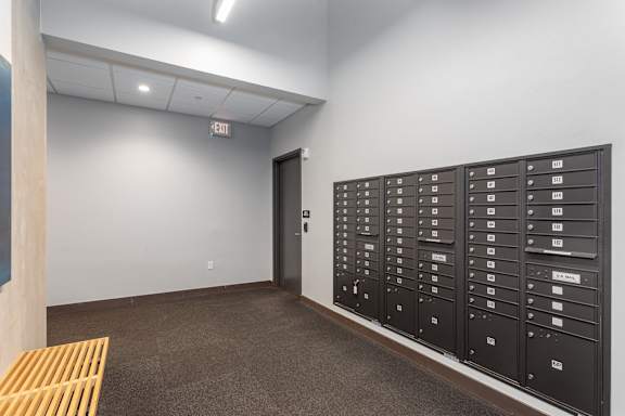 A room with a wall of mailboxes and a door.