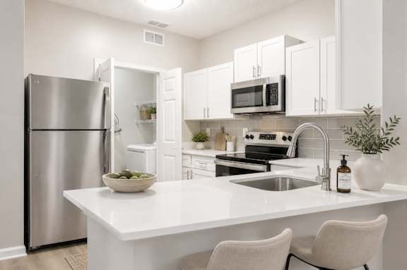A modern kitchen with a white countertop and stainless steel appliances.