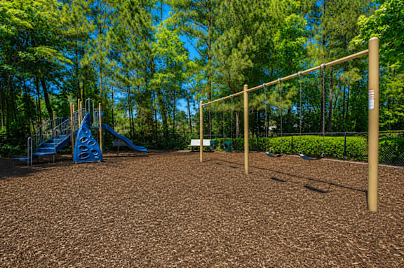 A playground with a slide, swings, and a monkey bars.
