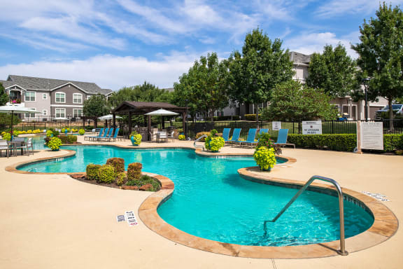 a swimming pool with chairs and umbrellas in front of a building