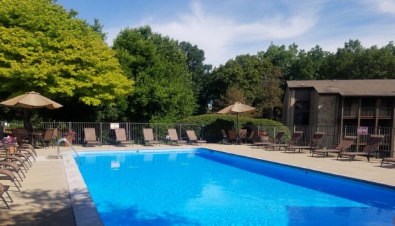 a swimming pool with chaise lounge chairs and umbrellas at Winchell Way Apartment , Kalamazoo, 49008