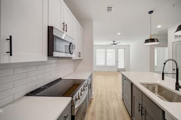A modern kitchen with white cabinets and a wooden floor.