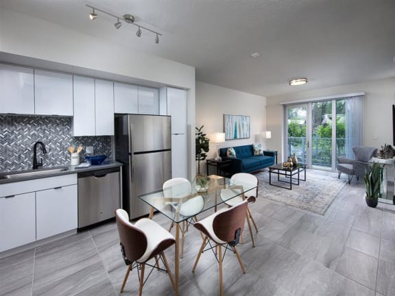 a kitchen and living room with white cabinets and stainless steel appliances at Saba Pompano Beach, Pompano Beach Florida
