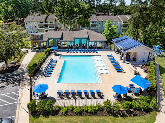 A large swimming pool surrounded by blue lounge chairs and umbrellas.