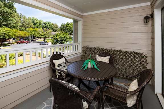 A patio with a table and chairs overlooking a parking lot.