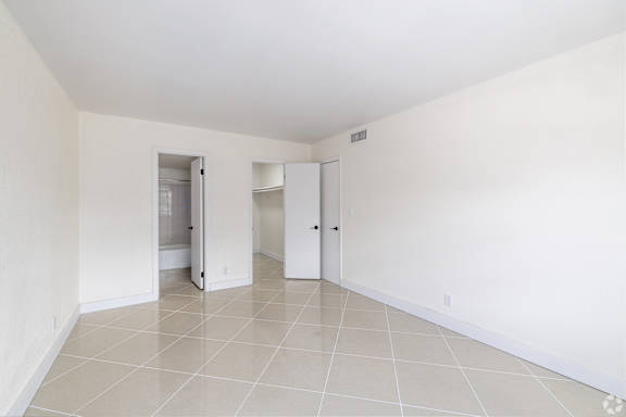 A white room with two doors and a tiled floor.