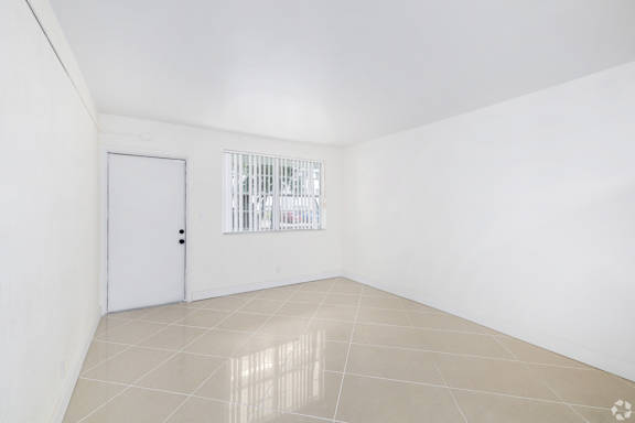 A white room with a door and a window with bars.