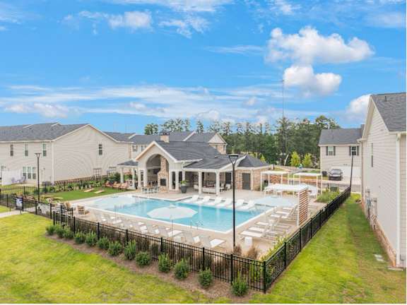 A pool surrounded by a black fence with a house in the background.