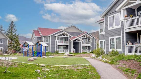 A playground area is located in front of a building with a red roof.