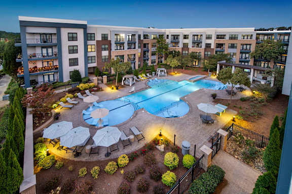 A swimming pool surrounded by a patio with chairs and umbrellas.