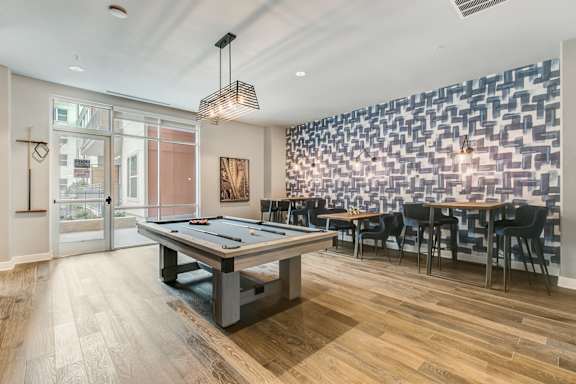 A room with a pool table and a wall of windows.