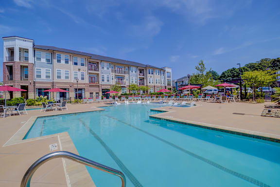 A large swimming pool in front of a multi-story apartment building.