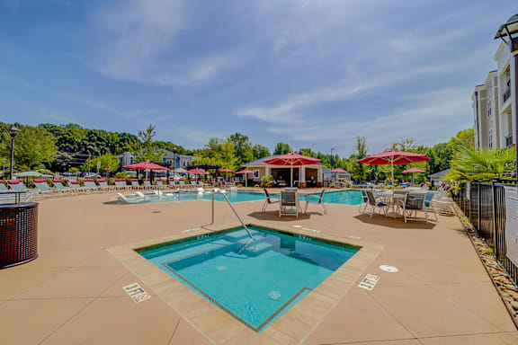 A large outdoor swimming pool with a hot tub and lounge chairs.