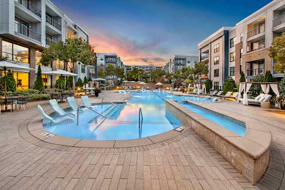 A large outdoor swimming pool surrounded by lounge chairs and umbrellas.