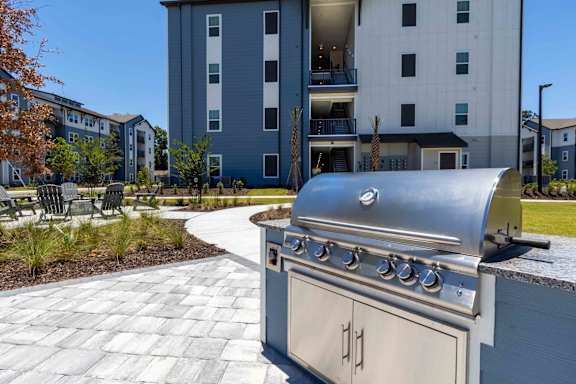 A silver grill is in the foreground of a residential area.