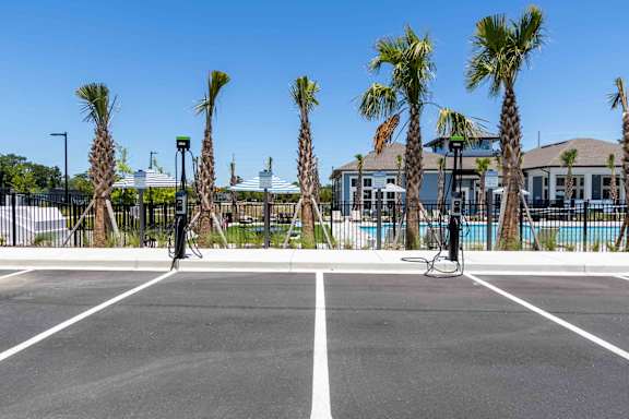 A tennis court surrounded by palm trees and a fence.