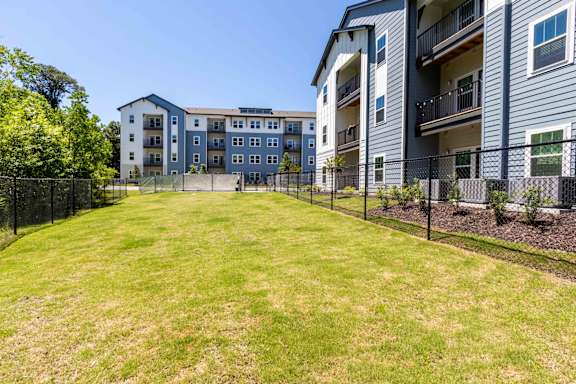 A large grassy area in front of a multi-story apartment building.