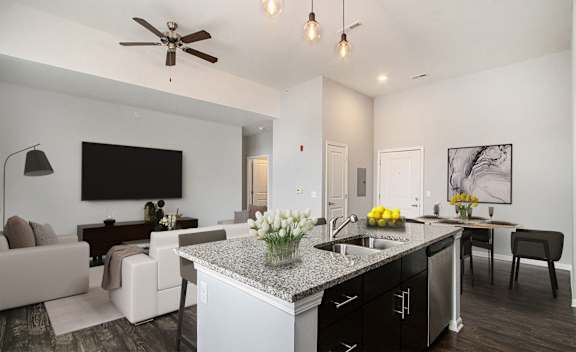 A modern kitchen with a large island and a living room area with a couch and a television.