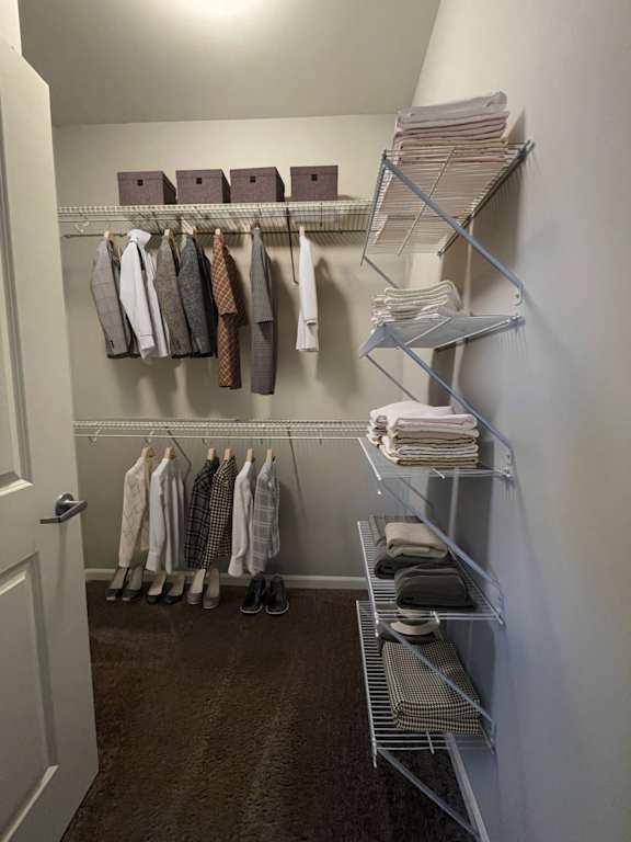 A hallway with a white door and a rack of ties and shirts.