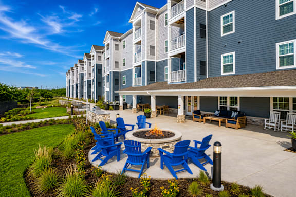 A large building with a blue and white exterior and a patio with blue chairs and a fire pit.