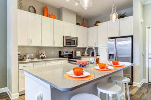 a kitchen with white cabinets and a counter with plates and cups on it