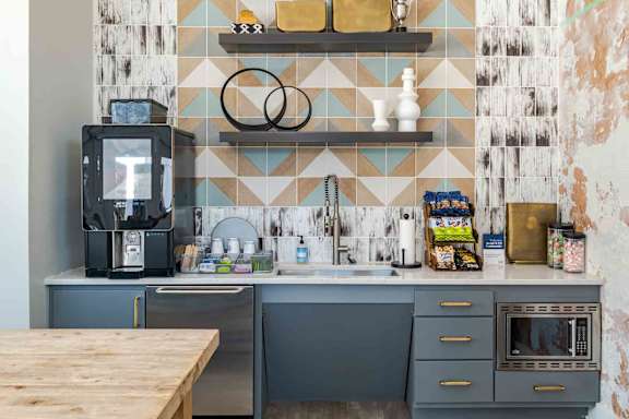 A kitchen with a wooden table in front of a blue and white tiled wall.