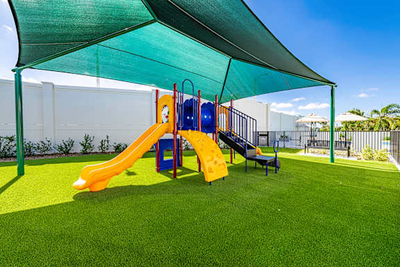 A playground with a yellow slide and a blue slide under a green canopy.