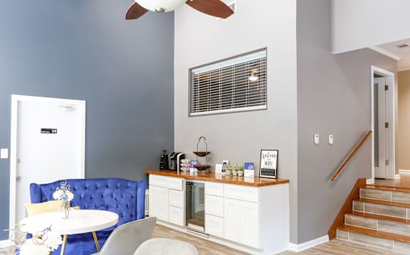 A blue sofa sits in a living room with a white table and a fan.