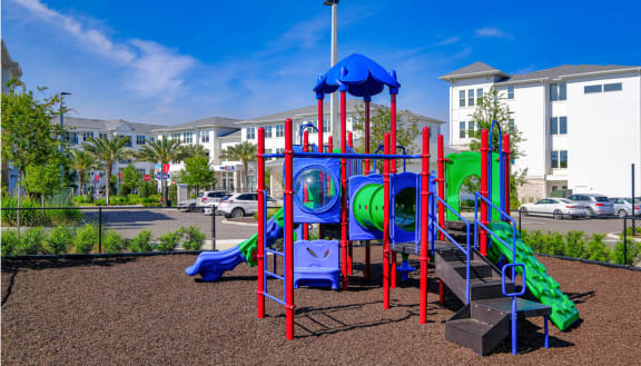 a playground with a blue and red play set in front of a building at Altis Grand Lake Willis, Florida