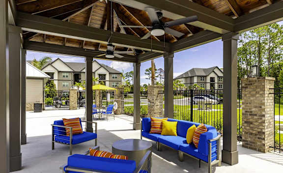 A patio with blue couches and a ceiling fan.